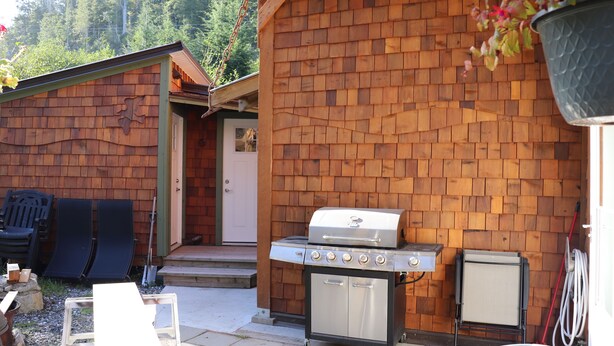 A wooden cabin with a grill and a small refrigerator.