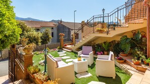 A courtyard with outdoor furniture, a staircase, and potted plants.