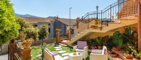 A courtyard with outdoor furniture, a staircase, and potted plants.