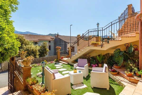 A courtyard with outdoor furniture, a staircase, and potted plants.
