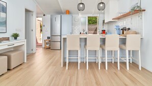 A modern kitchen with a central island, white cabinetry, and pendant lighting.