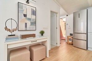 Una cocina moderna con encimera blanca, electrodomésticos de acero inoxidable y una puerta de cristal que da a un patio.