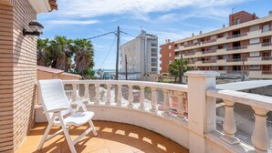 A balcony with white chairs, a tiled floor, and a view of a building with balconies. - Holiday Home 'Villa Jordi Y Nuri' with Private Terrace, Wi-Fi and Air Conditioning (Cambrils)
