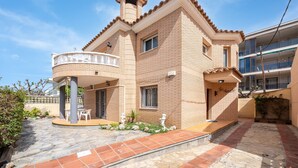 A two-story house with a balcony, a stone patio, and a small garden area. - Holiday Home 'Villa Jordi Y Nuri' with Private Terrace, Wi-Fi and Air Conditioning (Cambrils)