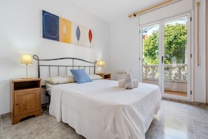 A bedroom with a bed, two bedside tables, a window with a view, and a wall with artwork.