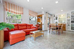 A living room with a red sofa, a coffee table, and a dining area with chairs.