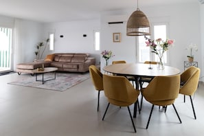 A modern living room with a sofa, coffee table, dining table, chairs, and a hanging light fixture. - Villa 'Rd01 Atalaya' with Sea View, Wifi and Air Conditioning (Torrox)