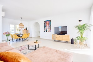 A modern living room with a sofa, dining table, chairs, a TV, and decorative plants. - Villa 'Rd01 Atalaya' with Sea View, Wifi and Air Conditioning (Torrox)