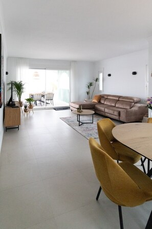 Ein modernes Wohnzimmer mit einer Couch, einem Esstisch, Stühlen und einer Küchenzeile.