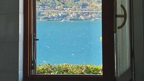 A window with a view of a lake, a mountain, and a bridge.