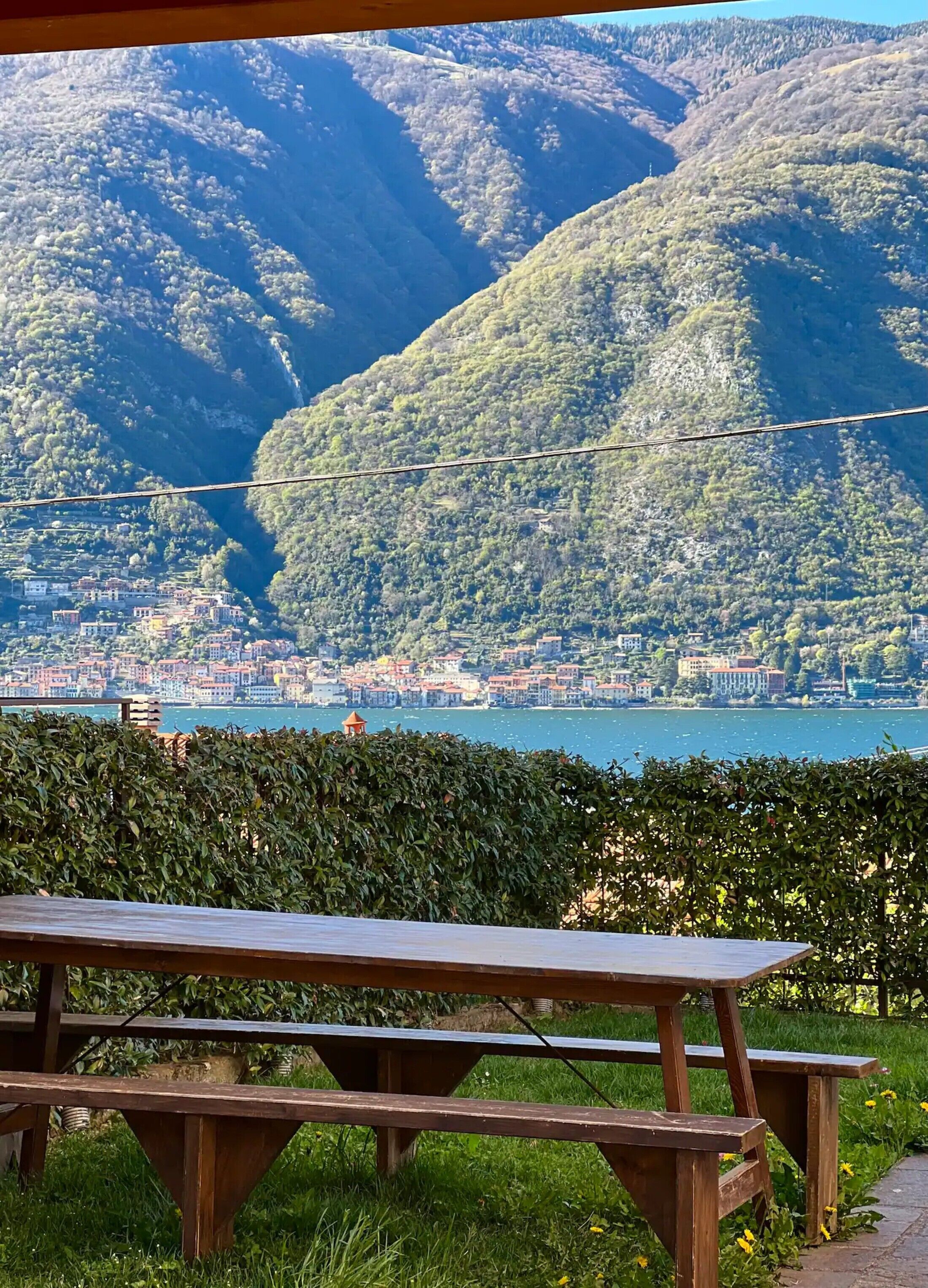 Een picknicktafel in een grasveld met uitzicht op een meer en een stad op de achtergrond.