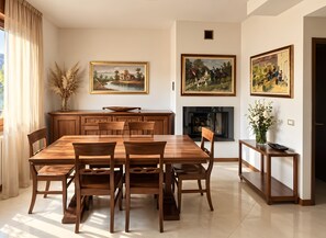 Ein Essbereich mit einem Holztisch und Stühlen, einer Vase mit Trockenpflanzen und zwei gerahmten Bildern an der Wand.