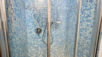 Eine gläserne Dusche mit einer Wand aus Fliesenmosaik.