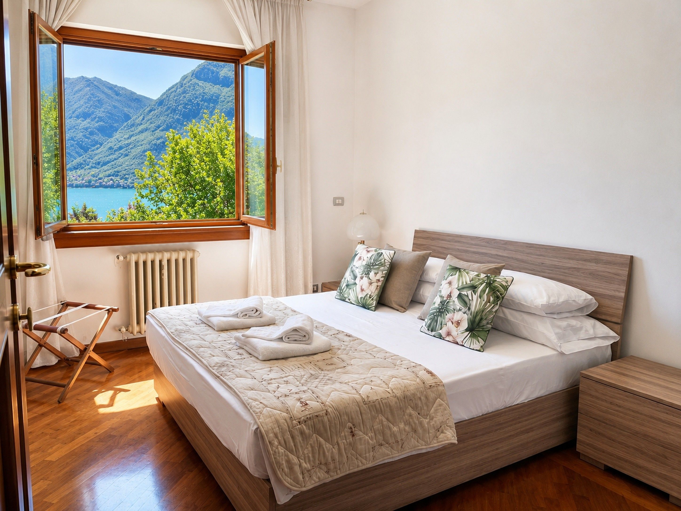 Quarto com uma janela grande, cama de madeira e vista para as montanhas.