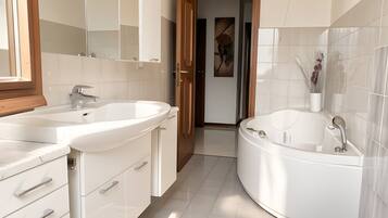 A modern bathroom with a double sink vanity, a freestanding bathtub, and a separate toilet.