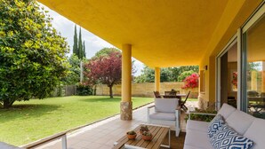 An outdoor patio area with a yellow roof, a white sofa with patterned cushions, a wooden table, and a potted plant. - Country House with Garden, Near Barcelona and with Sea Views (Sant Andreu de Llavaneres)