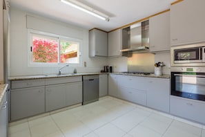 A modern kitchen with a dishwasher, microwave, oven, and granite countertop.