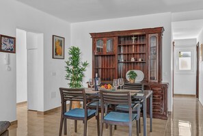 Un coin repas avec un buffet en bois, des chaises, une table dressée avec des assiettes, des verres et une plante.