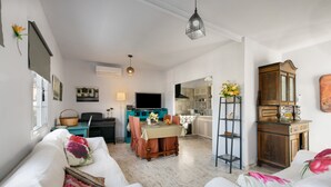Ein Wohnzimmer mit einer Couch, einem Esstisch und einem Fernseher.