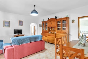 Un salon comprenant un canapé, un téléviseur, un meuble en bois et une table à manger.