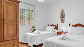 Een slaapkamer met twee bedden, een garderobe, een raam en een decoratie van een surfboard.