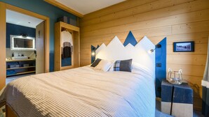 A bedroom with a bed, wooden headboard, a small bedside table, and a wall-mounted light fixture.