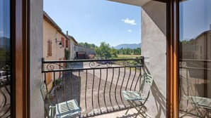 Un balcon avec une balustrade en métal, une vue sur un immeuble et un ciel dégagé.