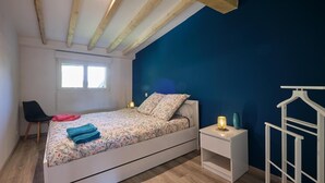 Une chambre à coucher comprenant un lit, une chaise, une table de chevet, une lampe et une armoire.