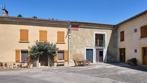 Un bâtiment doté d’une cour intérieure, de volets en bois, d’un balcon et de plantes en pot.