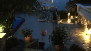 A pool area with a view of the water, potted plants, and a stone pathway. - Villa 'Beach  Alonissos For 6 People' with Shared Pool, Wi-Fi and Air Conditioning (Alonissos)