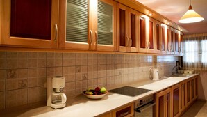 A kitchen with wooden cabinets, a coffee maker, a bowl of fruit, and a dishwasher. - Villa 'Beach  Alonissos For 6 People' with Shared Pool, Wi-Fi and Air Conditioning (Alonissos)
