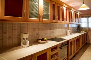 Una cocina con armarios de madera, una cafetera, un cuenco de fruta y un lavavajillas.
