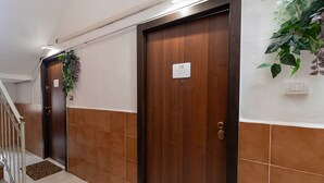 A hallway with two wooden doors, a staircase, and a wall-mounted light fixture. - Studio Apartment 'Elettra' with Wi-Fi and Air Conditioning (Bari)