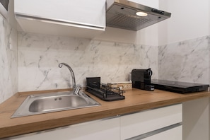 A kitchen with a stainless steel sink, a coffee machine, and a black induction cooktop.