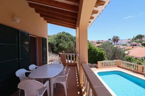 A poolside area with a table and chairs, a pool, and a view of a residential area. - Villa 'Diana' with Private Pool, Wi-Fi and Air Conditioning (Cala en Porter)