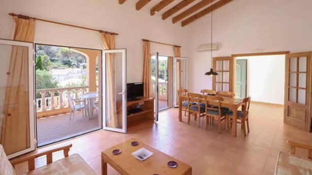 A spacious room with a balcony, a dining area, and a television. - Villa 'Diana' with Private Pool, Wi-Fi and Air Conditioning (Cala en Porter)