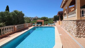 A swimming pool with a stone wall and a building with a balcony. - Villa 'Diana' with Private Pool, Wi-Fi and Air Conditioning (Cala en Porter)