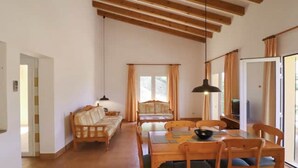 A room with a wooden dining table, chairs, a sofa, and a television. - Villa 'Diana' with Private Pool, Wi-Fi and Air Conditioning (Cala en Porter)