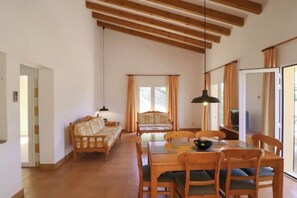 A room with a wooden dining table, chairs, a sofa, and a television. - Villa 'Diana' with Private Pool, Wi-Fi and Air Conditioning (Cala en Porter)