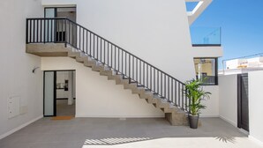 Un escalier moderne menant à un balcon agrémenté d’un pot de fleurs.