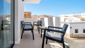Un balcon avec des chaises et une table, donnant sur un paysage montagneux.