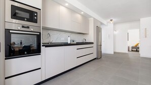 Une cuisine moderne dotée d’appareils électroménagers intégrés, un coin repas et une salle de bain visible.
