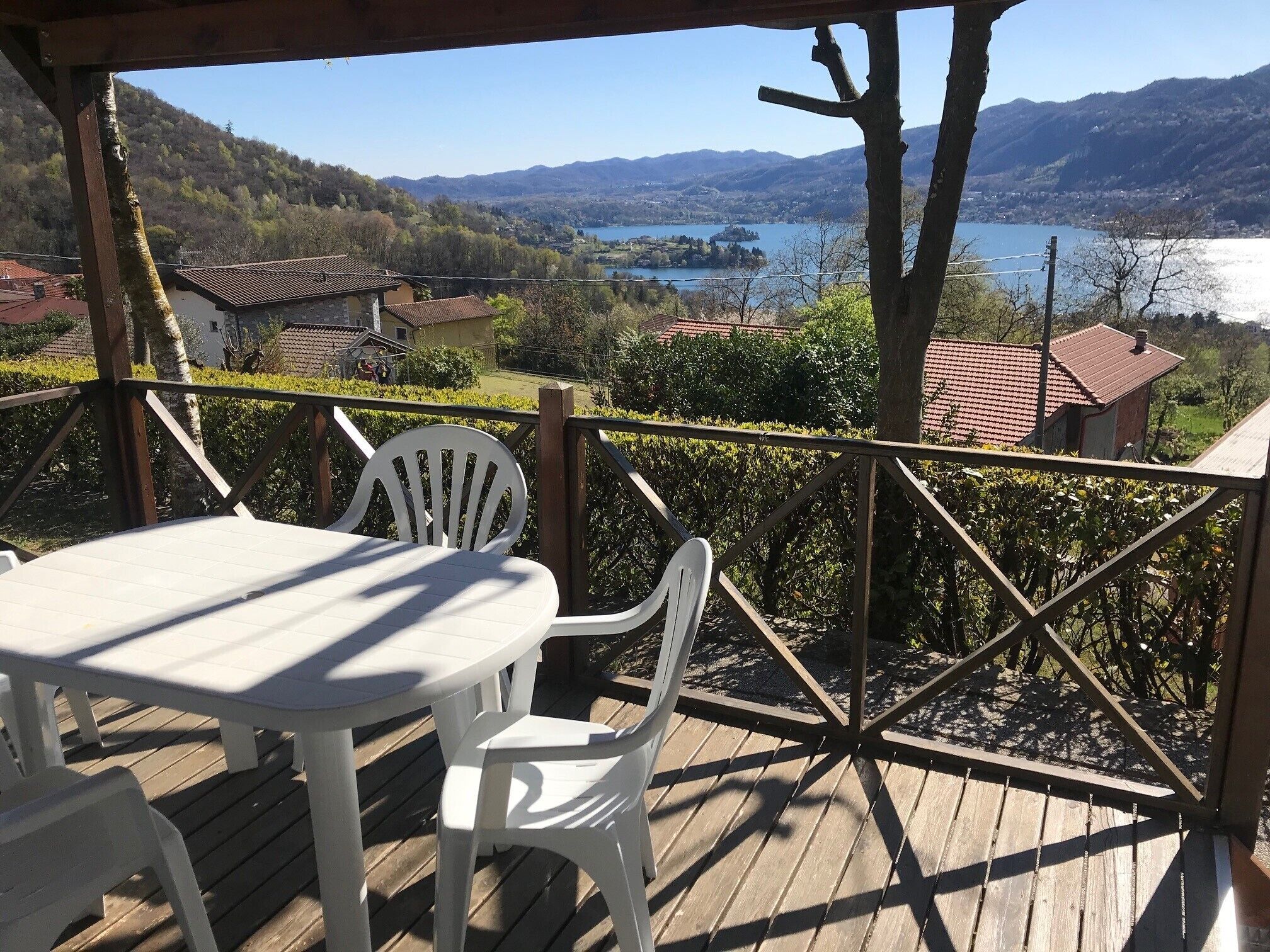 Una terraza de madera con una mesa y sillas, con vistas a un lago y montañas.