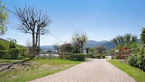 Un camino pavimentado que atraviesa un área ajardinada con árboles y vistas a montañas distantes.