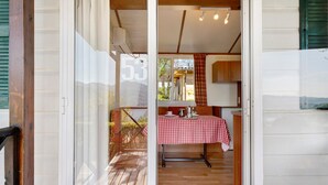 Una habitación con una mesa a cuadros, suelo de madera y vistas a través de un ventanal.