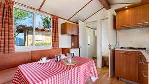 Una habitación con una mesa a cuadros, un sofá, una kitchenette y una ventana con cortinas.