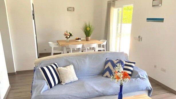 Una sala de estar moderna con un sofá, una mesa de centro y un comedor con sillas y una mesa.
