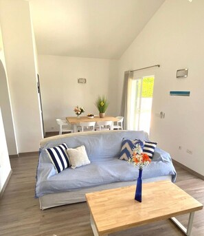 Un salon moderne comprenant un canapé, une table basse et un coin repas avec des chaises et une table.