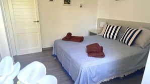 Un dormitorio con cama, almohadas, una mesita de noche y una puerta.