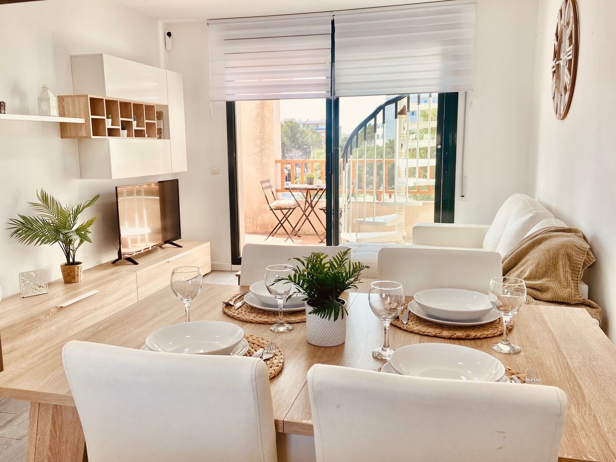 Een eetgedeelte met een houten tafel voor vier personen, witte stoelen en uitzicht op het buitenterras.